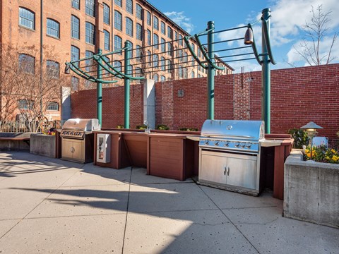 a row of barbecue pits on a sidewalk in front of a brick building