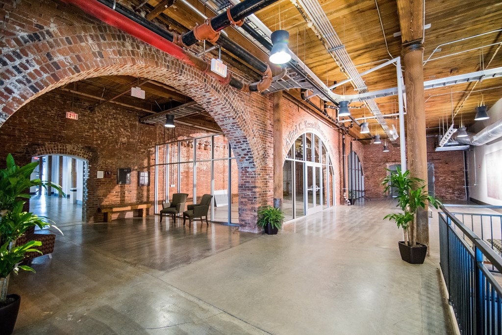 a large room with a large archway and a lobby with chairs and plants