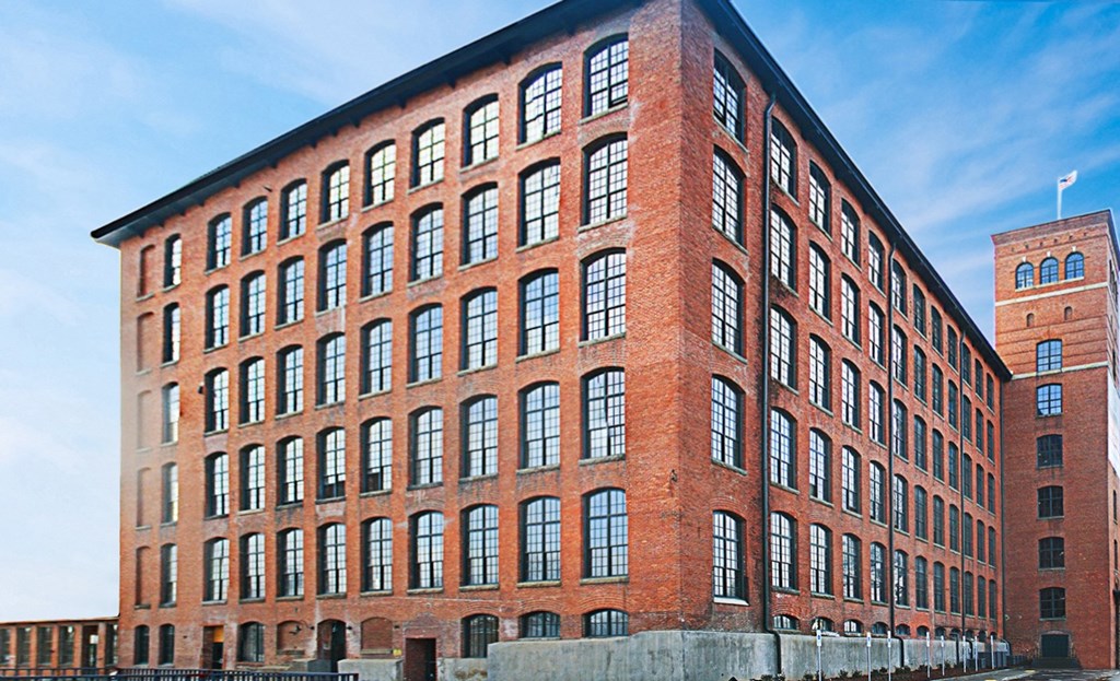 a red brick building with many windows and a clock tower in the background
