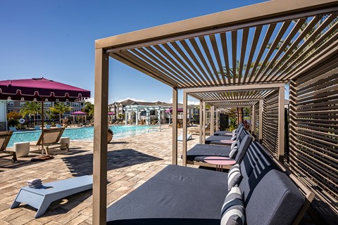 A poolside area with sun loungers and a shaded pergola.