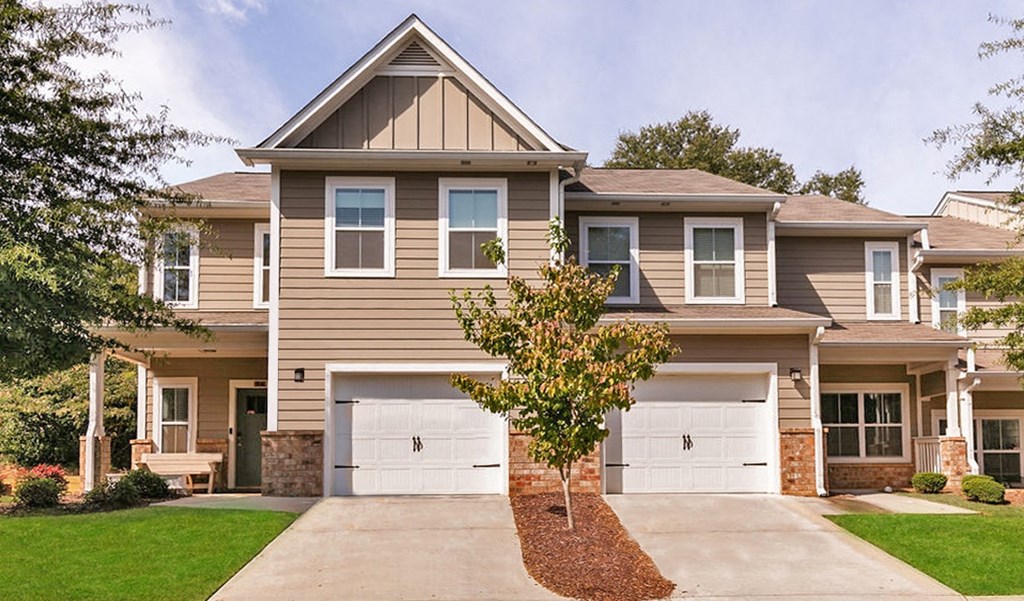a tan house with white garage doors