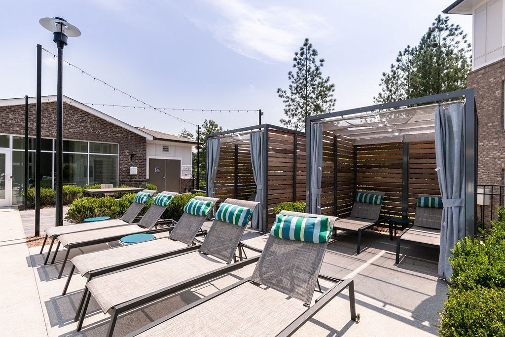 a group of lounge chairs on a patio with a building in the background