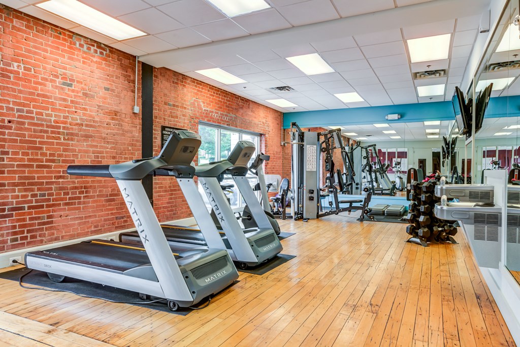 a gym with cardio machines and weights on a wooden floor