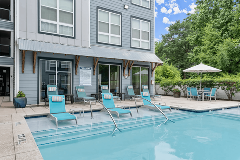 A pool with chairs and a building in the background.