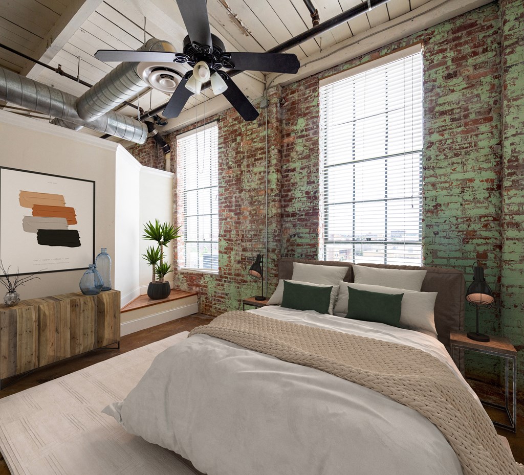 a bedroom with a bed and exposed brick walls and a ceiling fan