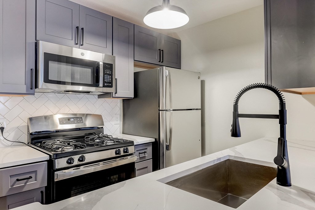 a kitchen with gray cabinets and white countertops