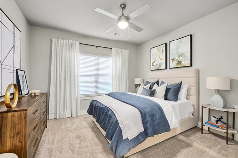 A bedroom with a bed, nightstand, and a ceiling fan.