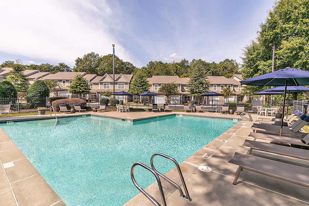 a swimming pool with chairs and umbrellas at the enclave at woodbury apartments
