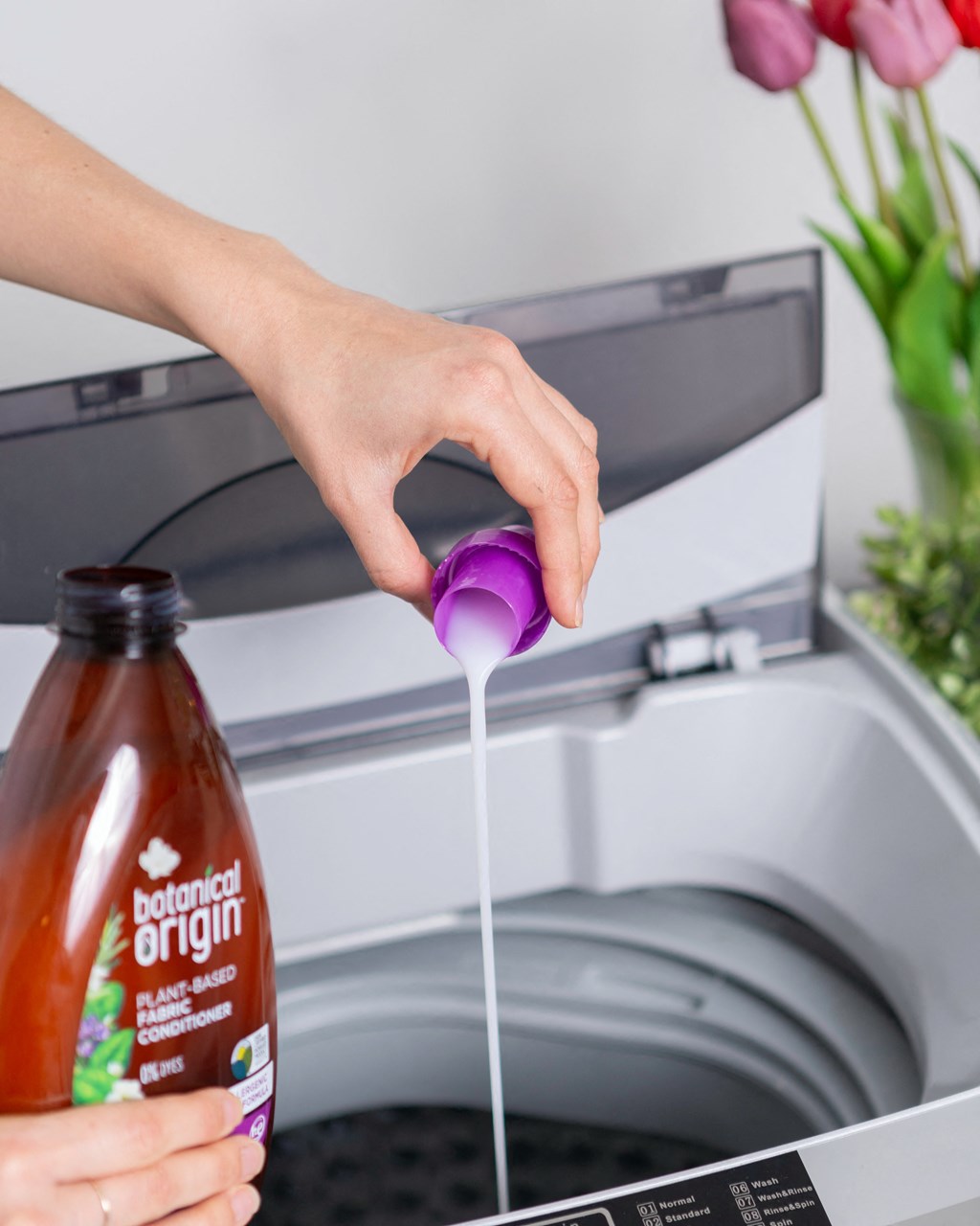 a person pouring a bottle of sauce into a washing machine