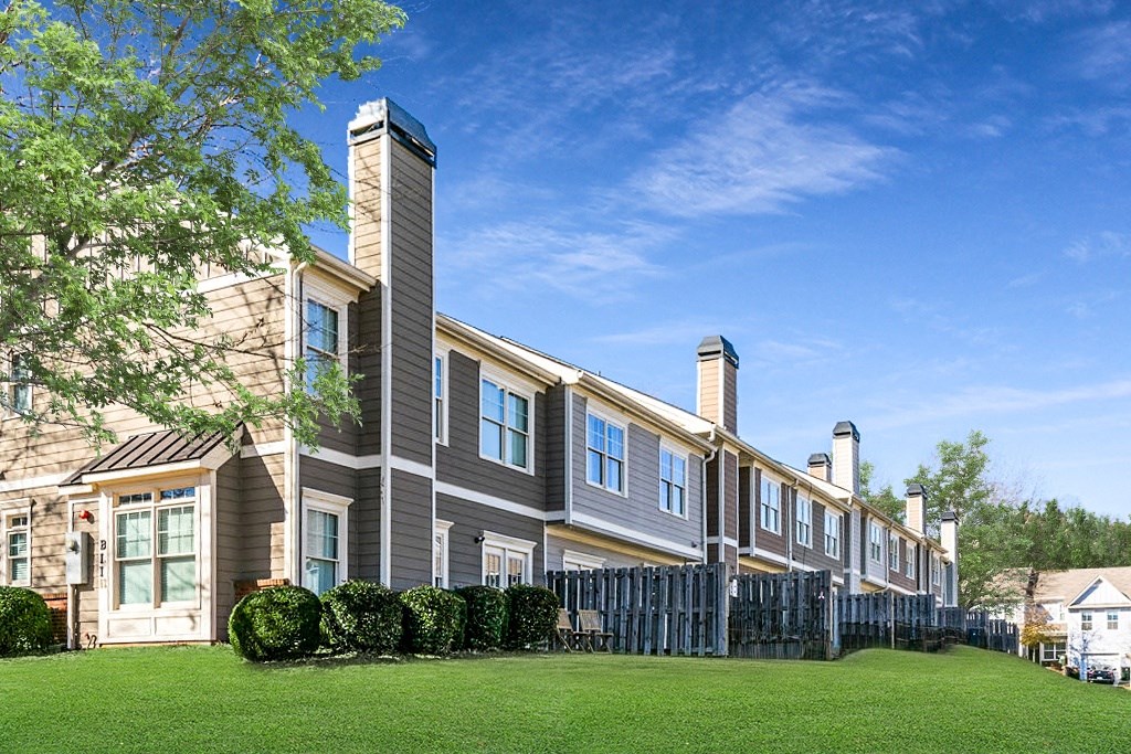 a row of townhomes with green grass and a blue sky