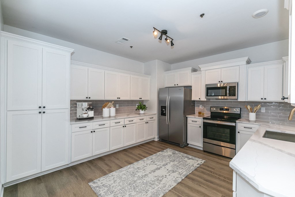 a large kitchen with white cabinets and stainless steel appliances