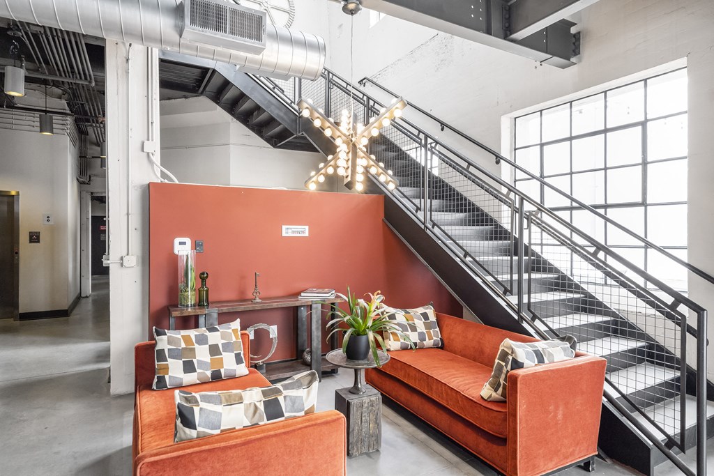 a living room with orange couches and a staircase