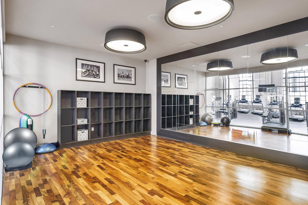 a gym with mirrors and a wooden floor and a workout area