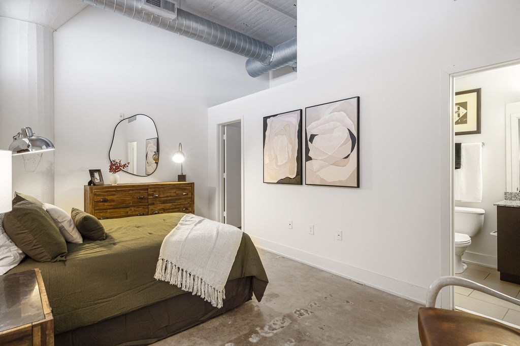 a bedroom with a bed and a toilet in a room with white walls