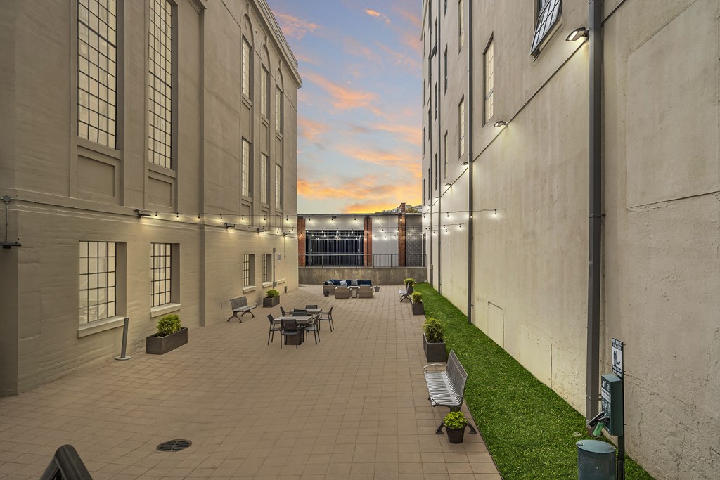 a patio with tables and chairs in a courtyard between two buildings