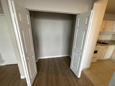 A kitchen with a white door open to a room with a wooden floor.