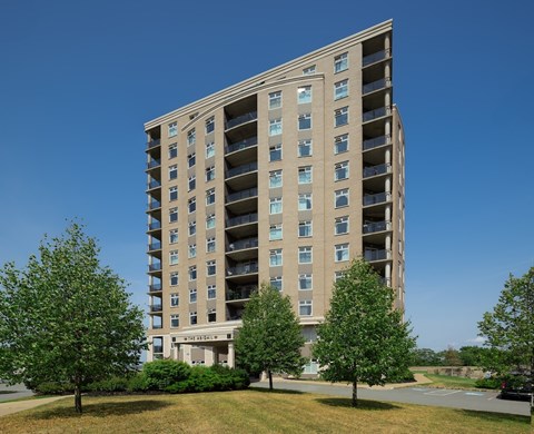A tall residential building with a green lawn in front.