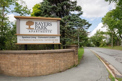 A sign for Bayers Park Apartments is displayed in front of a brick wall.
