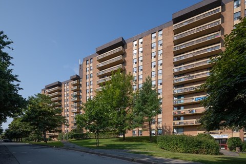 A large apartment building with a green lawn in front.