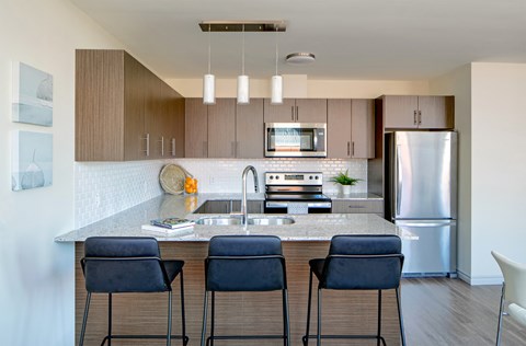 a kitchen with stainless steel appliances and a island with three chairs