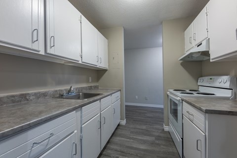 A kitchen with white cabinets and a marble countertop.