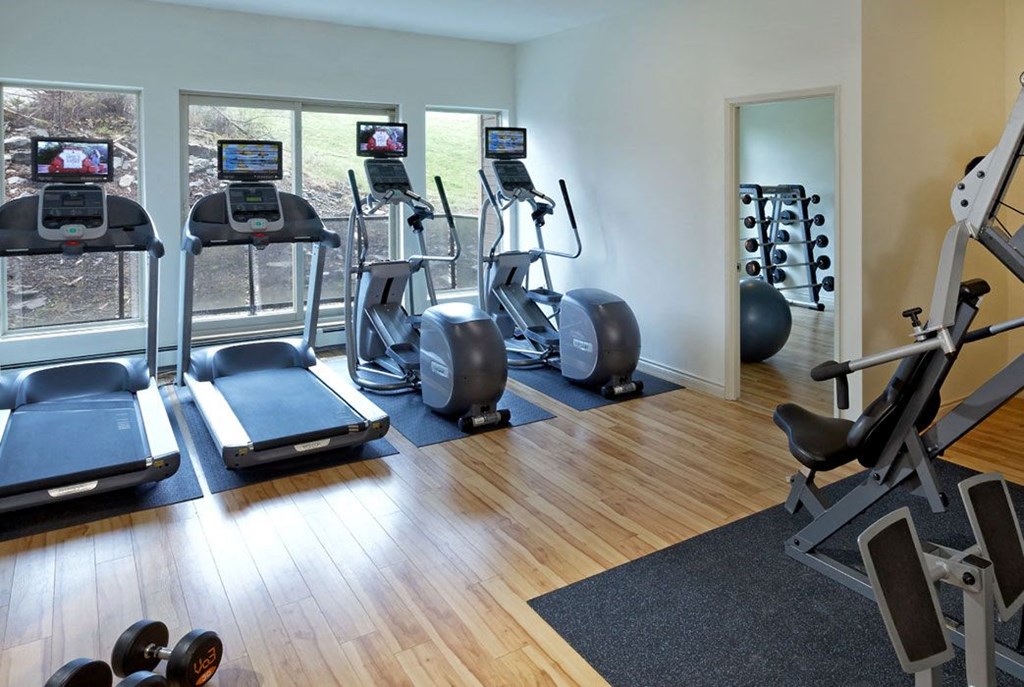 a gym with cardio equipment on the floor and windows