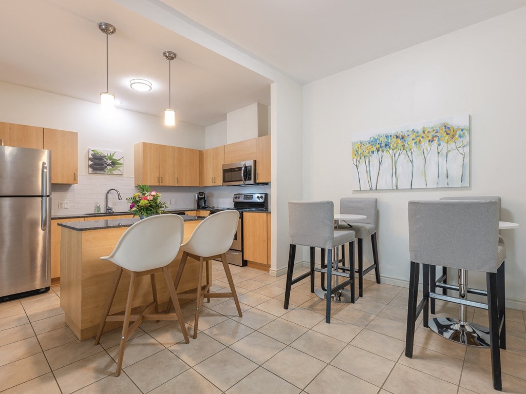A kitchen with a refrigerator, microwave, and bar stools.