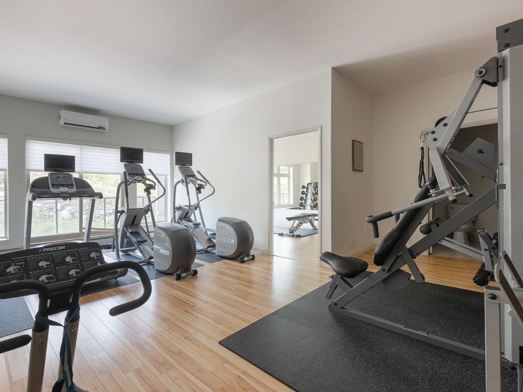 A gym with a treadmill, elliptical machines, and other exercise equipment.
