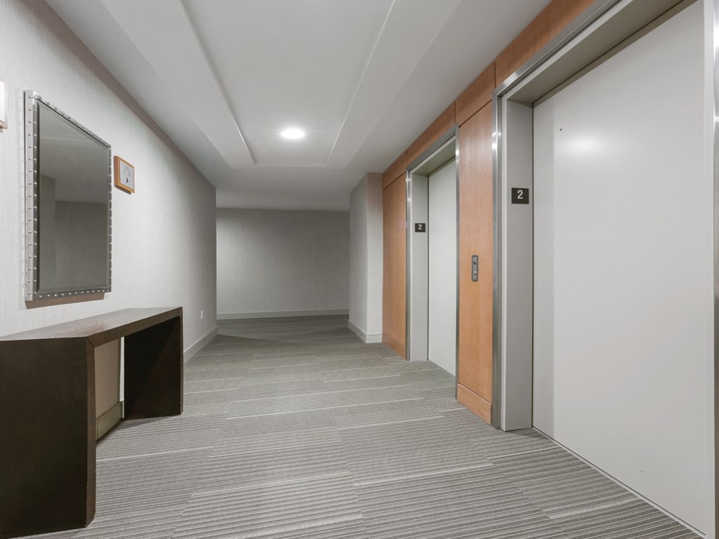 A hallway with a brown door and a mirror on the wall.