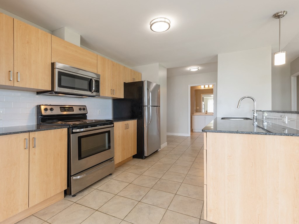A kitchen with wooden cabinets and a stainless steel refrigerator.