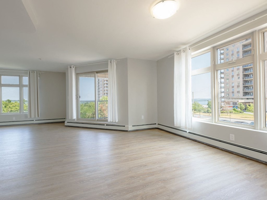 A large empty room with wooden floors and large windows.