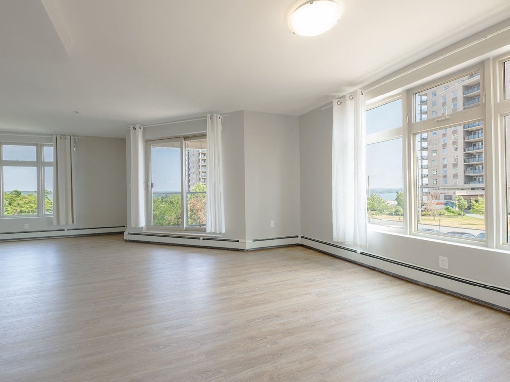 A large empty room with wooden floors and large windows.