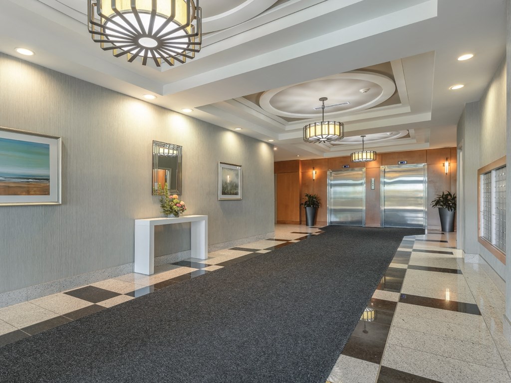 A hallway with a black and white checkered floor and a chandelier hanging from the ceiling.