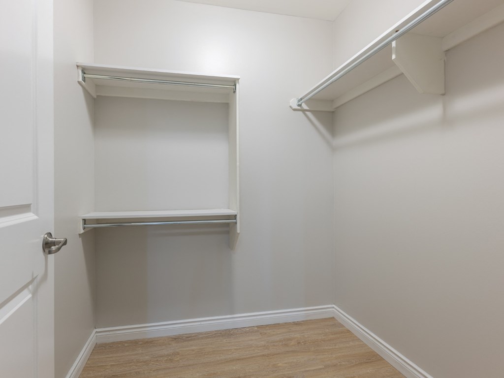 A white door is on the left of a room with a shelf.