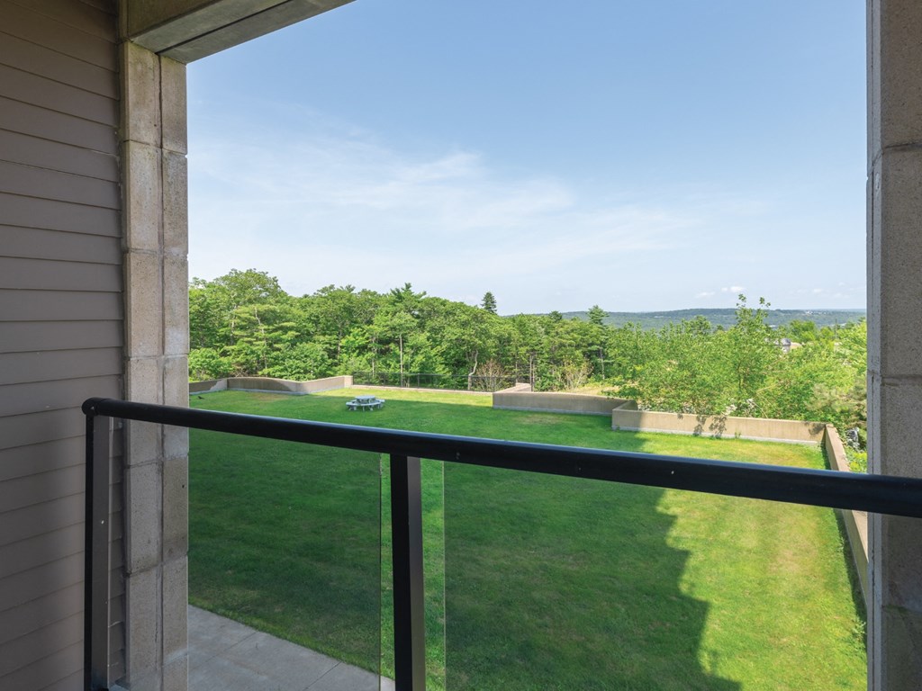 A balcony overlooks a green lawn and trees.