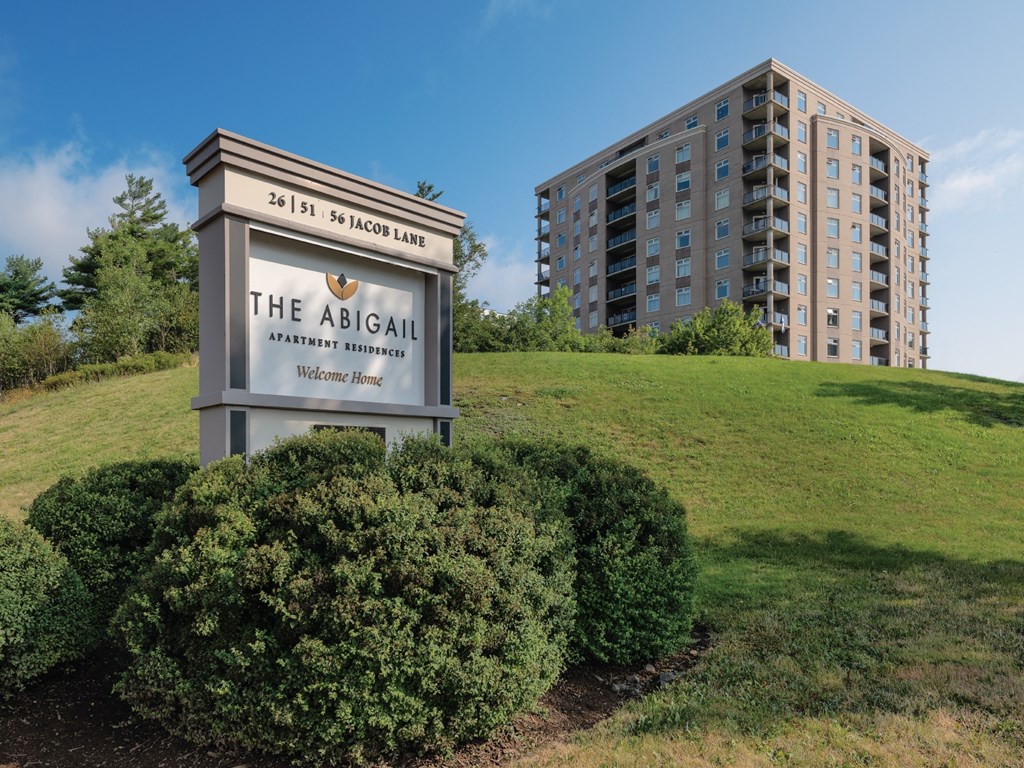 A sign for The Abigail Apartment Residence stands in front of a large building.