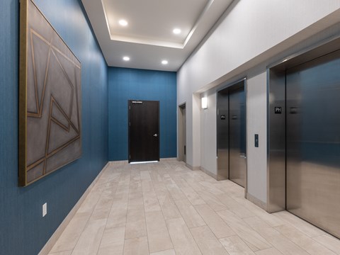 A hallway with a blue wall and a large painting on the left side.