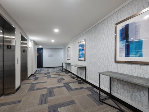 A hallway with a bench and a painting on the wall.