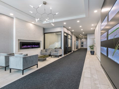 A modern living room with a grey carpet and a fireplace.