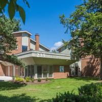 a large brick house with a green lawn and trees