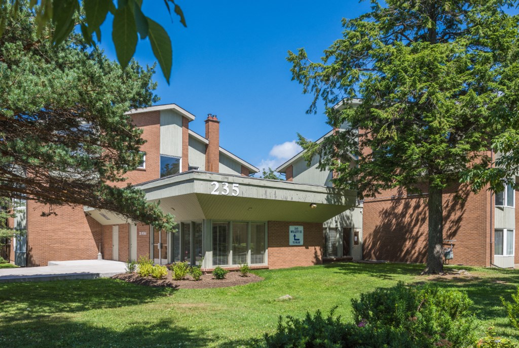 a large brick building with a green lawn and trees
