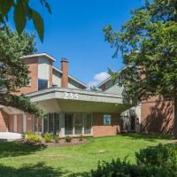 a large brick house with a green lawn and trees