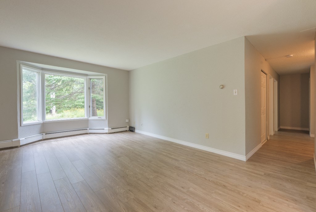 an empty living room with wood floors and a large window