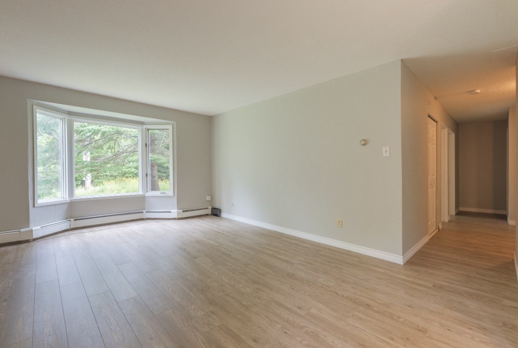 an empty living room with wood floors and a large window