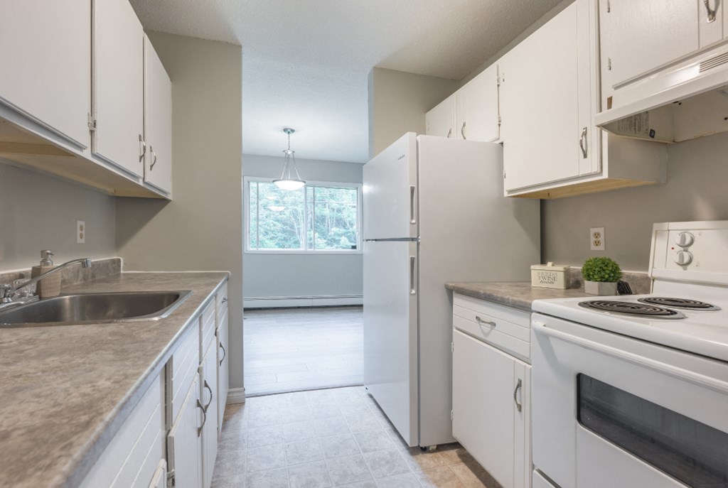 an empty kitchen with white appliances and white cabinets