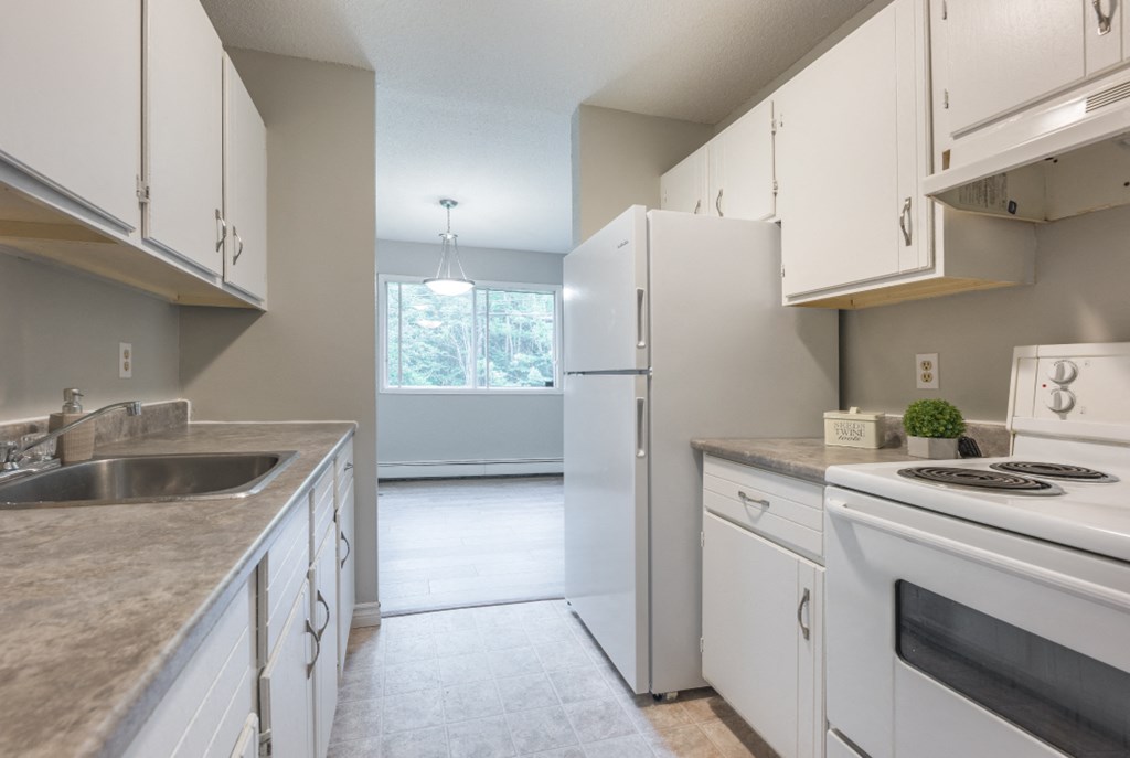 an empty kitchen with white appliances and white cabinets