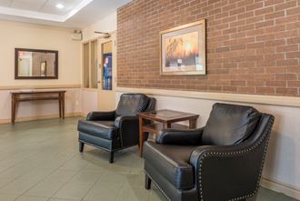 a waiting room with leather chairs and a brick wall