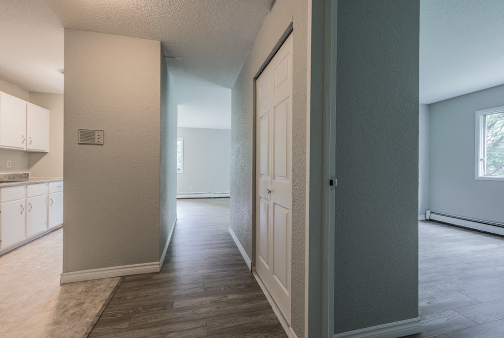an empty kitchen and hallway with a door open to the living room