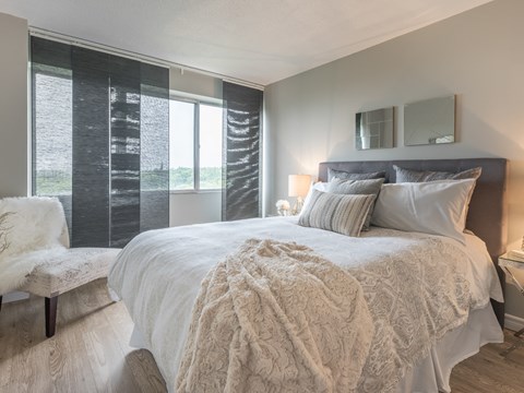 A bedroom with a large bed and a window with curtains.
