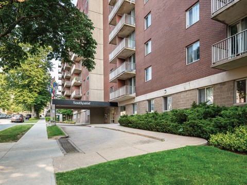 A red brick apartment building with a green lawn in front.